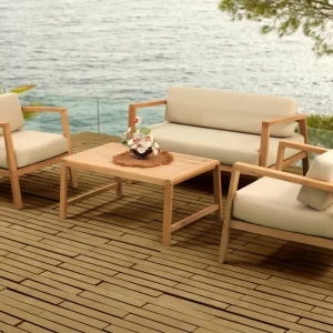 Outdoor seating set with wooden frames and cream cushions on a deck overlooking the ocean.