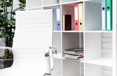 A close-up of a white storage solution bookshelf with various folders, books, and magazine.