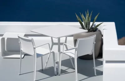 A white outdoor steel furniture dining set with a square table and two chairs.